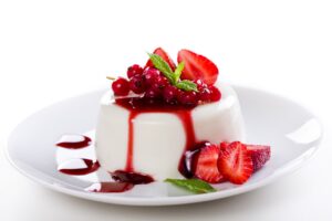 Close up photograph of a tasty panna cotta with red fruits